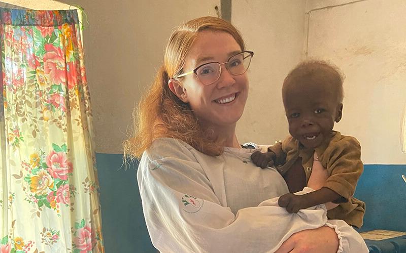 博彩平台推荐 alumna and Peace Corps volunteer Mackenzie Hafer with a child in a Madagascar health clinic