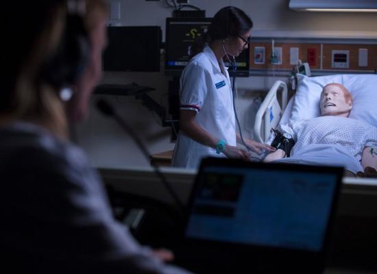 nursing students in an experiental classroom working with an artificial patient